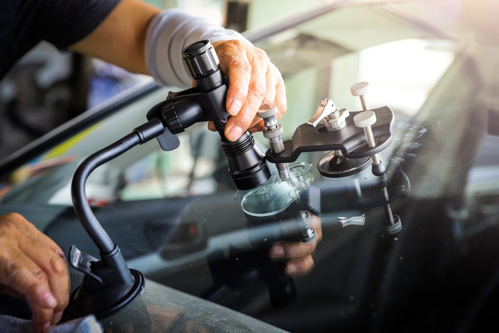 Windshield chip repair on a car using a suction-mounted specialized repair tool.